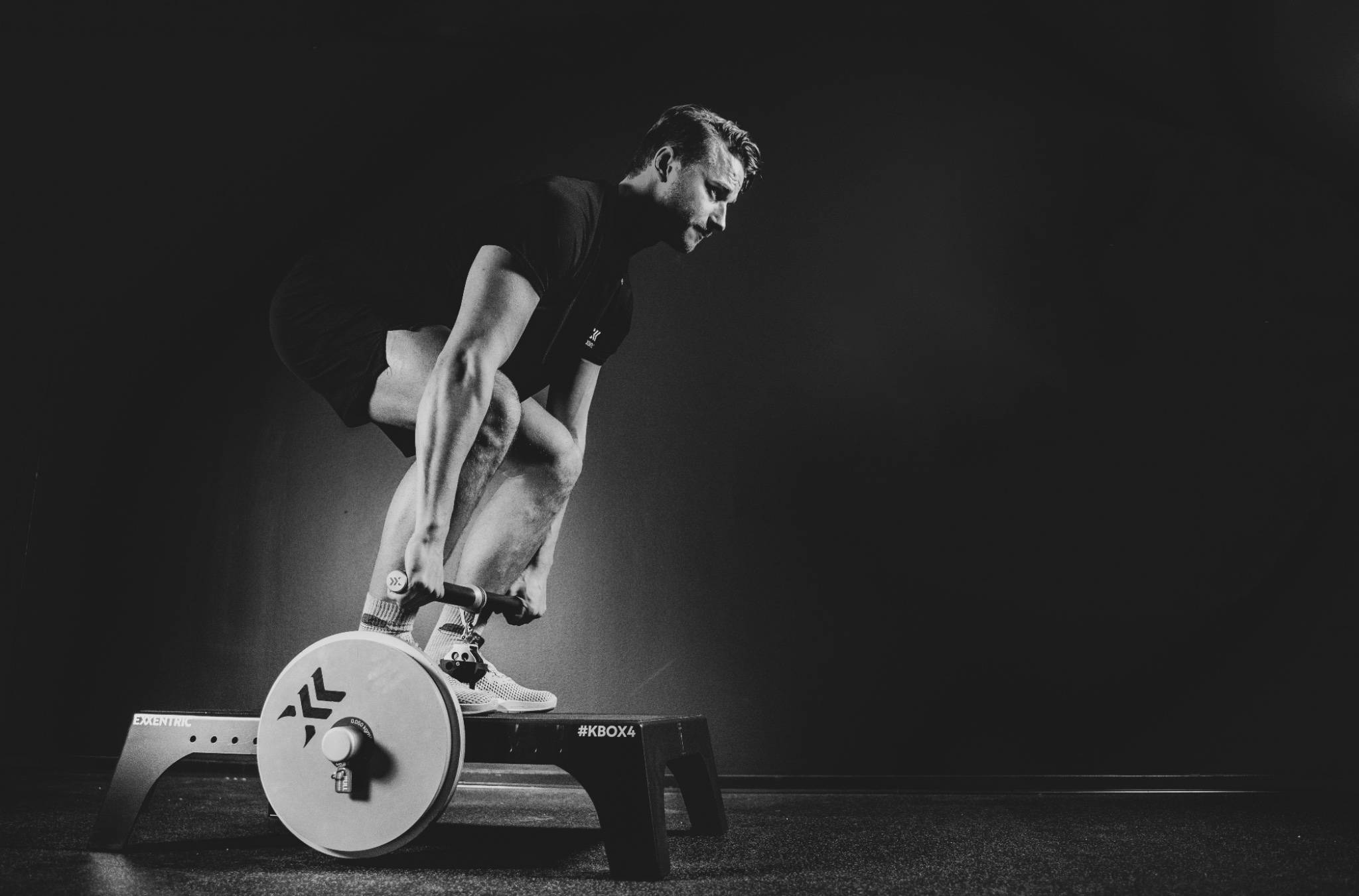 Black and white photo of Anton deadlifting heavy with a kBar on a kBox4 Pro with an advanced flywheel knob
